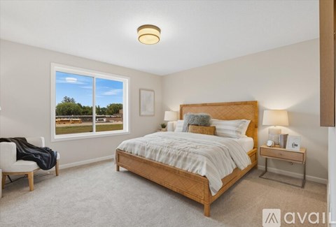 A bedroom with a large bed and a chair by the window.