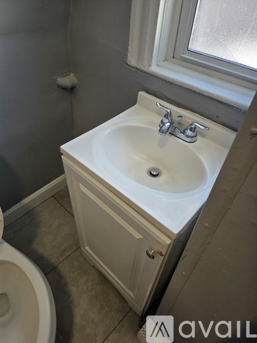 A white sink in a bathroom with a toilet and a window.