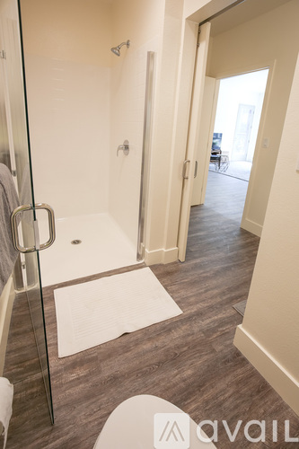 A bathroom with a glass shower stall and a white toilet.