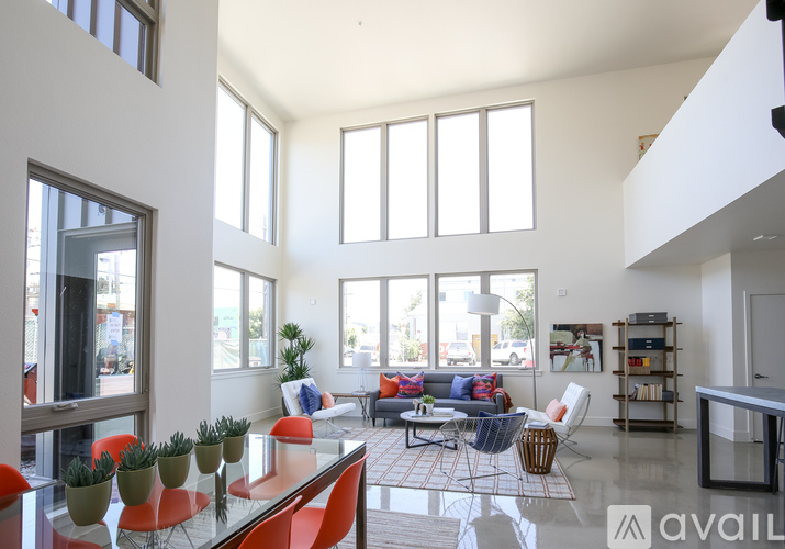 A living room with a glass table and orange chairs.
