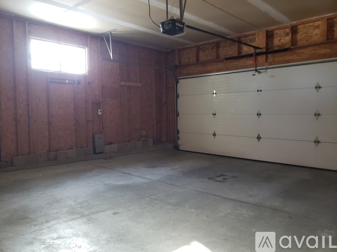 A spacious garage with a white door and a window letting in natural light.
