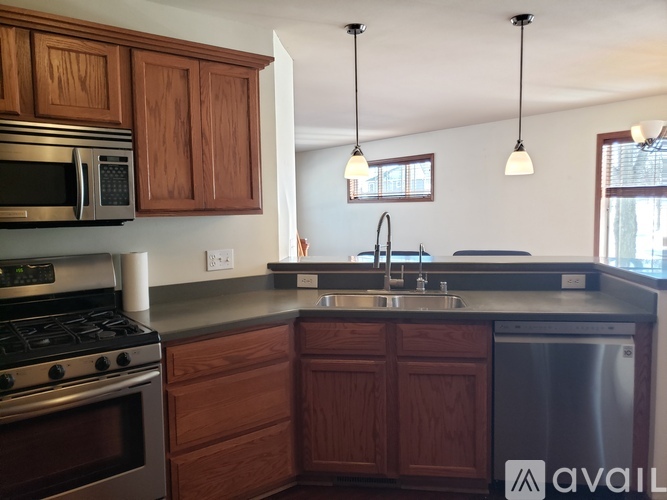 A kitchen with wooden cabinets and a stainless steel dishwasher.