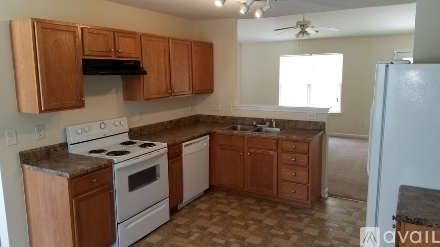 A kitchen with a white stove and wooden cabinets.