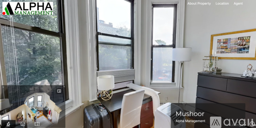 A room with a desk, chair, and a window overlooking a tree-filled street.