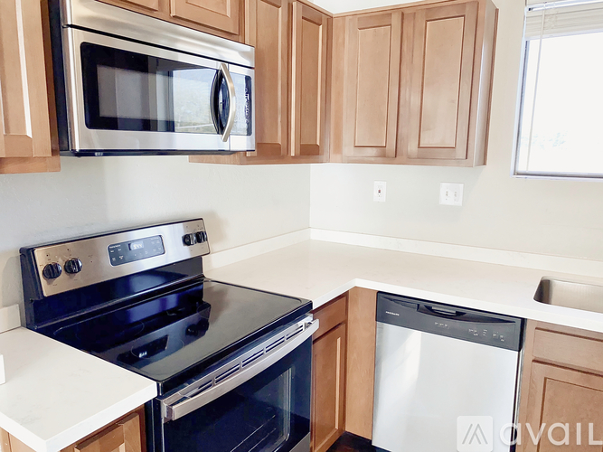 A kitchen with a black stove top oven, a silver microwave, and a white dishwasher.