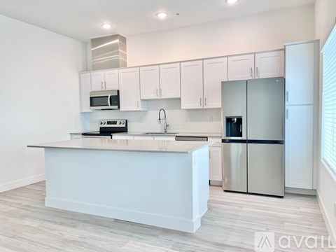 A kitchen with white cabinets and a stainless steel refrigerator.