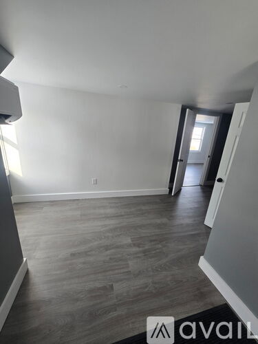 A room with wooden flooring and white walls.