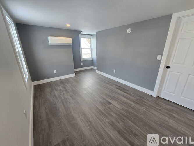 A room with grey walls and wooden flooring is available for rent.
