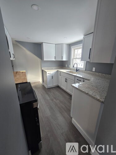 A kitchen with a black counter top and white cabinets.