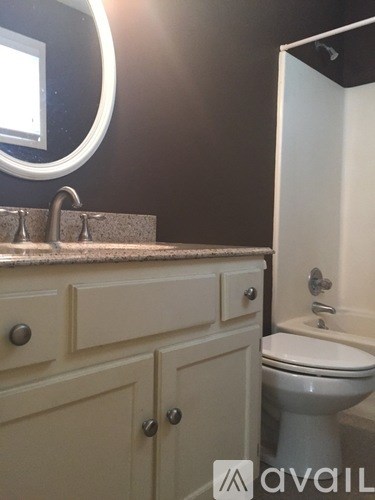 A bathroom with a toilet and a vanity with a mirror.