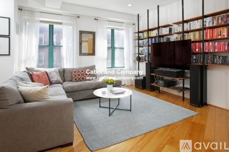 A living room with a grey couch, a white coffee table, and a bookshelf filled with books.