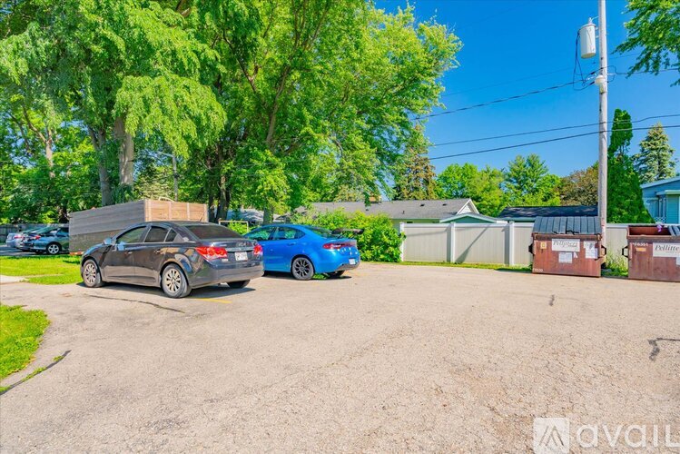 Two cars parked in a driveway with trees and a house in the background.