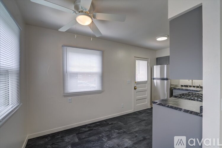 A kitchen area with a fan, a window with blinds, and a stove top oven.