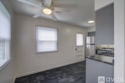 A kitchen area with a fan, a window with blinds, and a stove top oven.