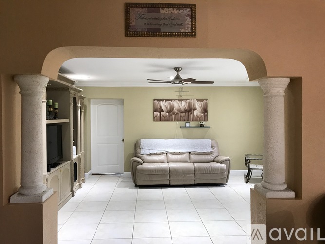 A living room with a couch, television, and a fan.
