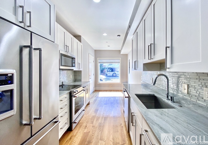 A kitchen with stainless steel appliances and wooden floors.