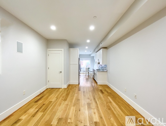 A long hallway with wooden floors and white walls.