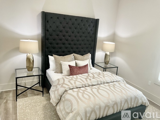 A bed with a black headboard and a white comforter with a pattern on it.