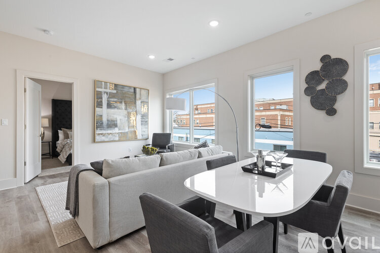 A modern living room with a grey couch and a white dining table.