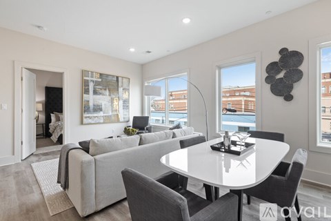 A modern living room with a grey couch and a white dining table.