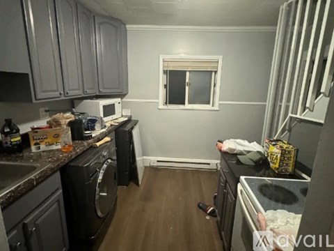 A kitchen with a washing machine and a microwave.