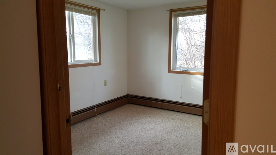 A room with two windows and carpeted floor.