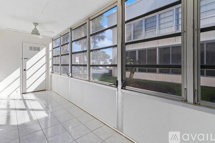 A hallway with a white tiled floor and a row of windows.