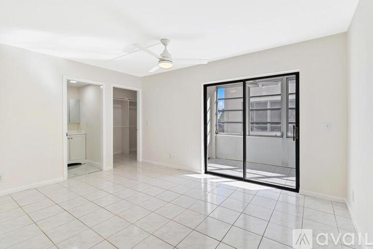 A spacious room with a ceiling fan and a sliding glass door.