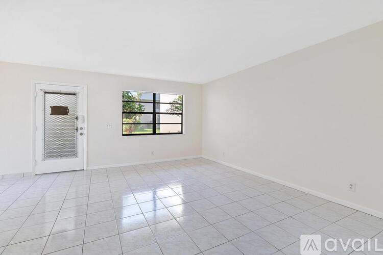 A room with a white door and a window with a view of trees.