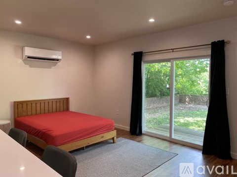 A bedroom with a red bedspread and a wooden headboard.
