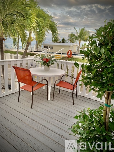A table with two chairs is on a deck with a view of the ocean.