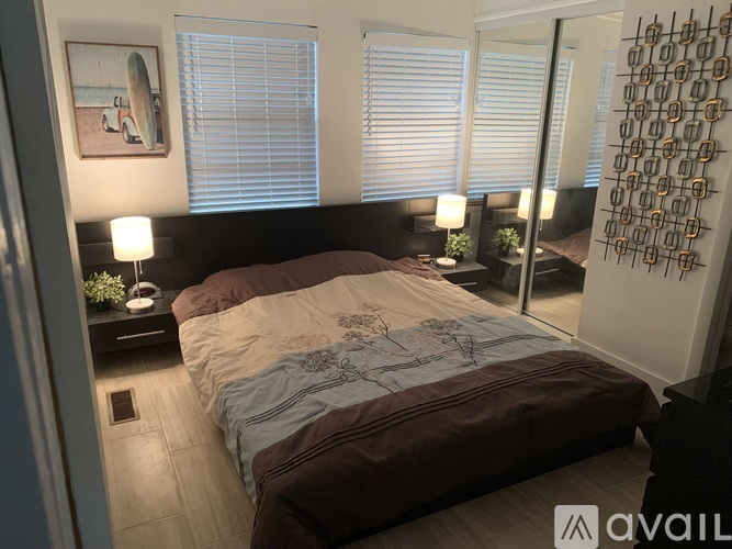 A bedroom with a large bed and a surfboard picture on the wall.