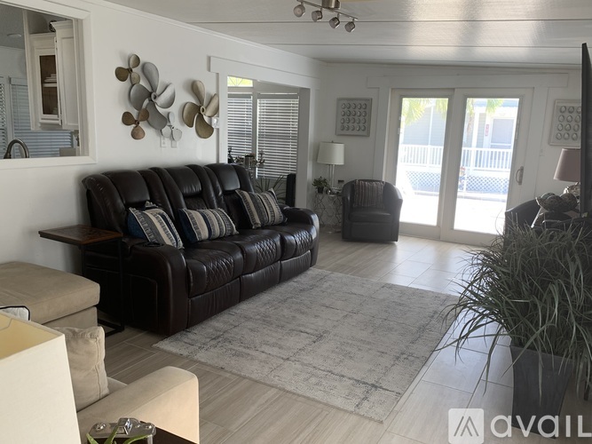 A living room with a black leather couch and a rug.