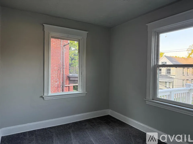 A room with two windows, one of which has a view of a red building.