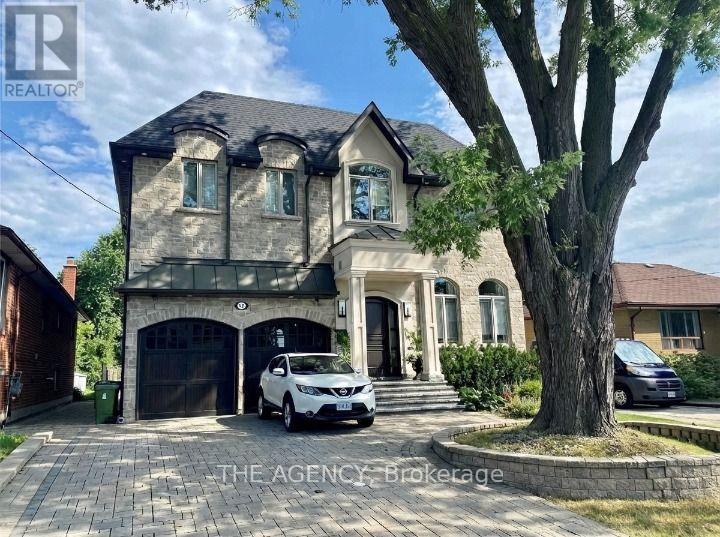 A house with a car parked in front and a tree to the right.