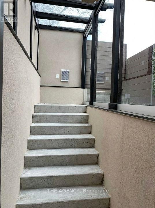 A set of concrete stairs leads up to a glass roofed area.