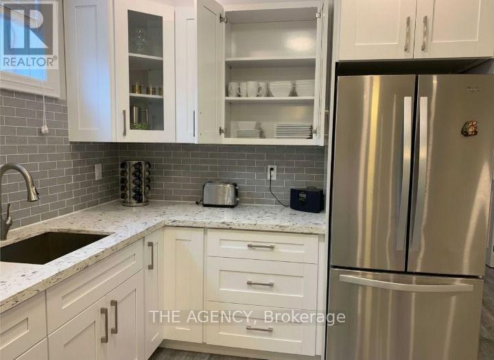 A kitchen with white cabinets and a stainless steel refrigerator.