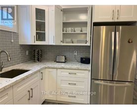 A kitchen with white cabinets and a stainless steel refrigerator.