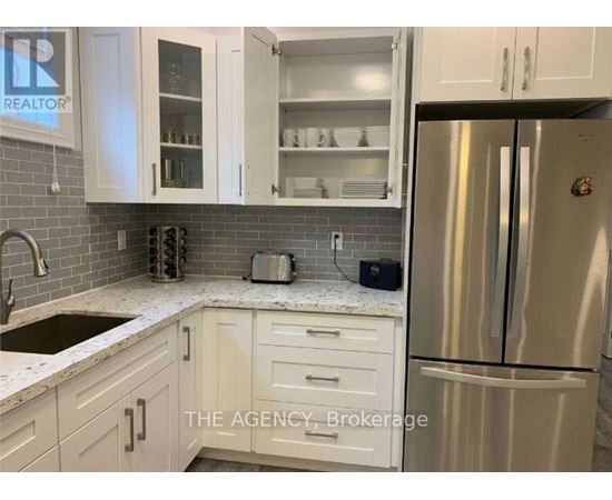 A kitchen with white cabinets and a stainless steel refrigerator.
