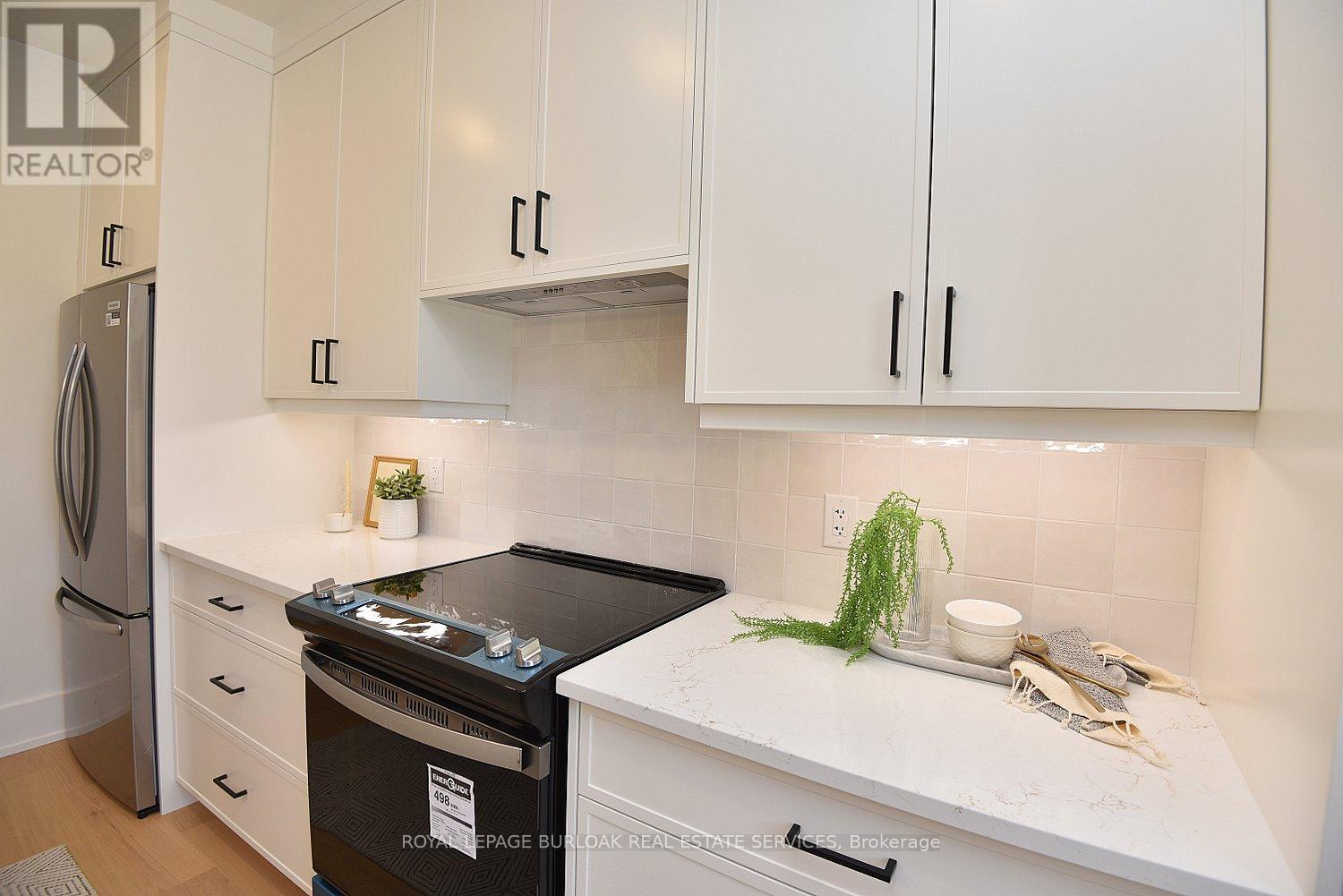 A white kitchen with a black stove top oven.