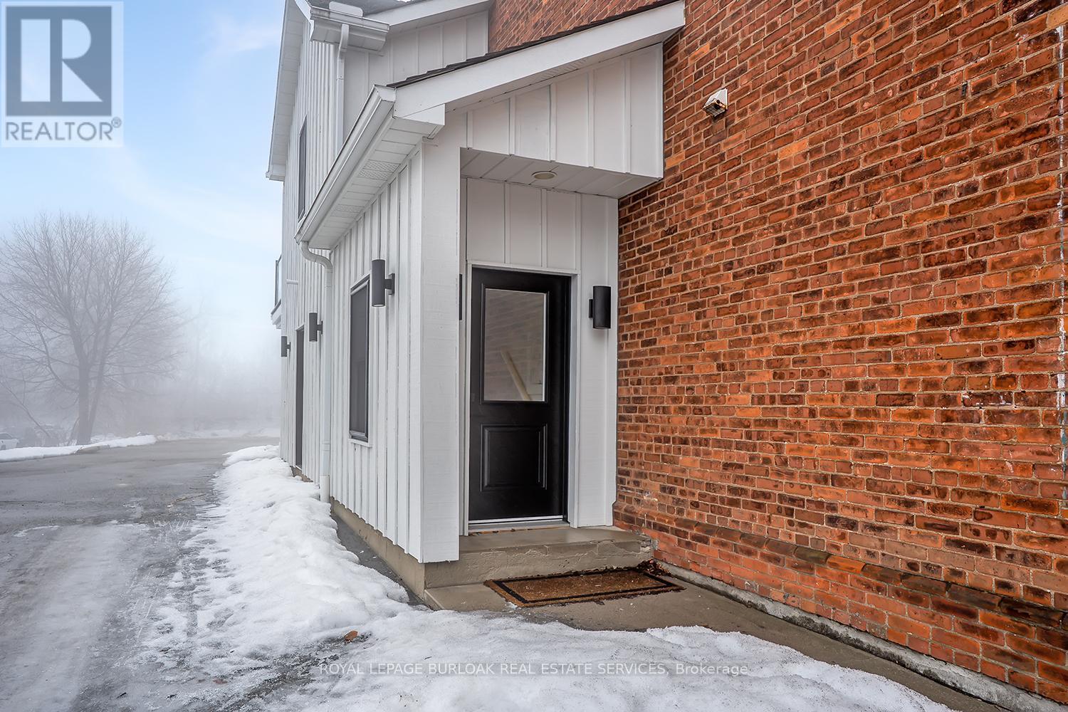 A small brick building with a white door and windows.