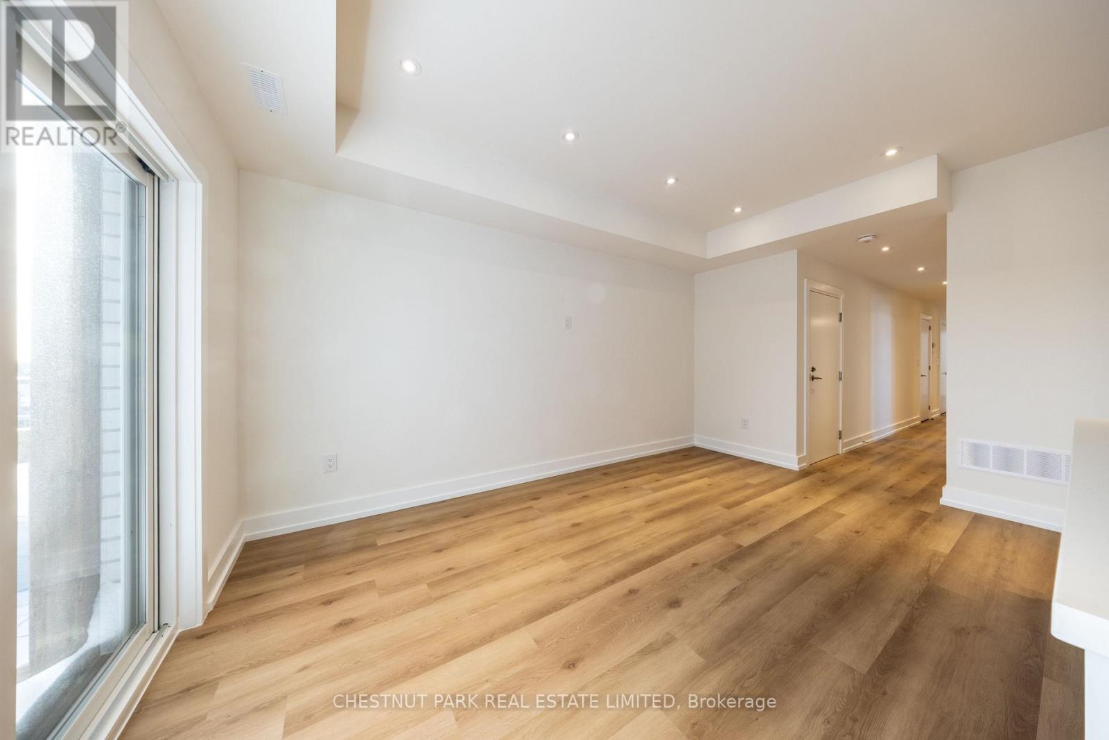 A spacious room with wooden flooring and white walls.