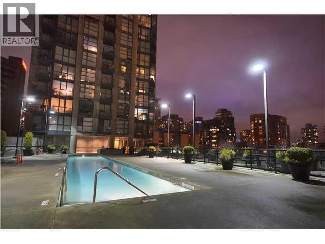 A swimming pool in a courtyard surrounded by buildings at night.