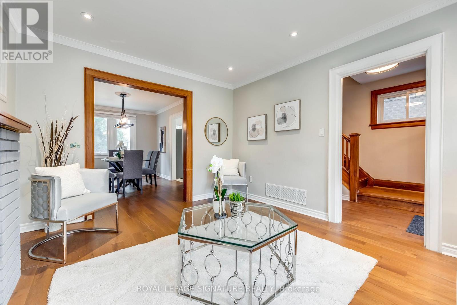 A living room with a glass coffee table and a mirror on the wall.
