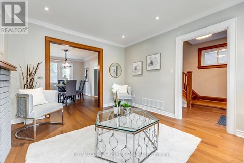 A living room with a glass coffee table and a mirror on the wall.