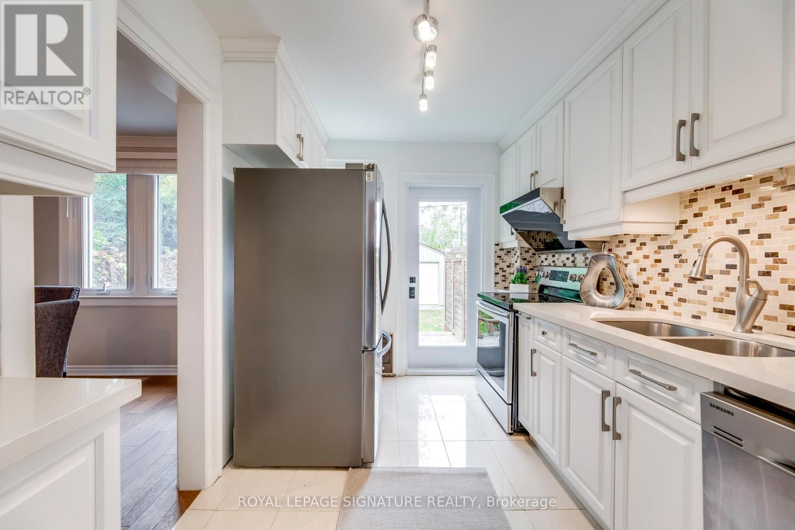 A kitchen with a refrigerator and a sink.