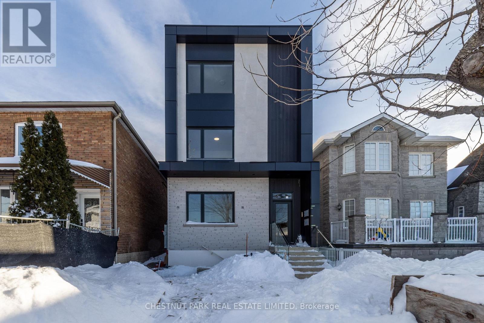 A modern house with a large front yard and a snow-covered ground.