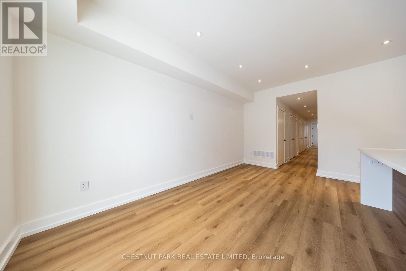 A spacious room with wooden flooring and white walls.