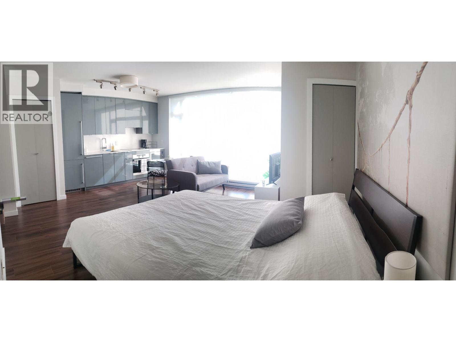 A bedroom with a bed, a nightstand, and a window.