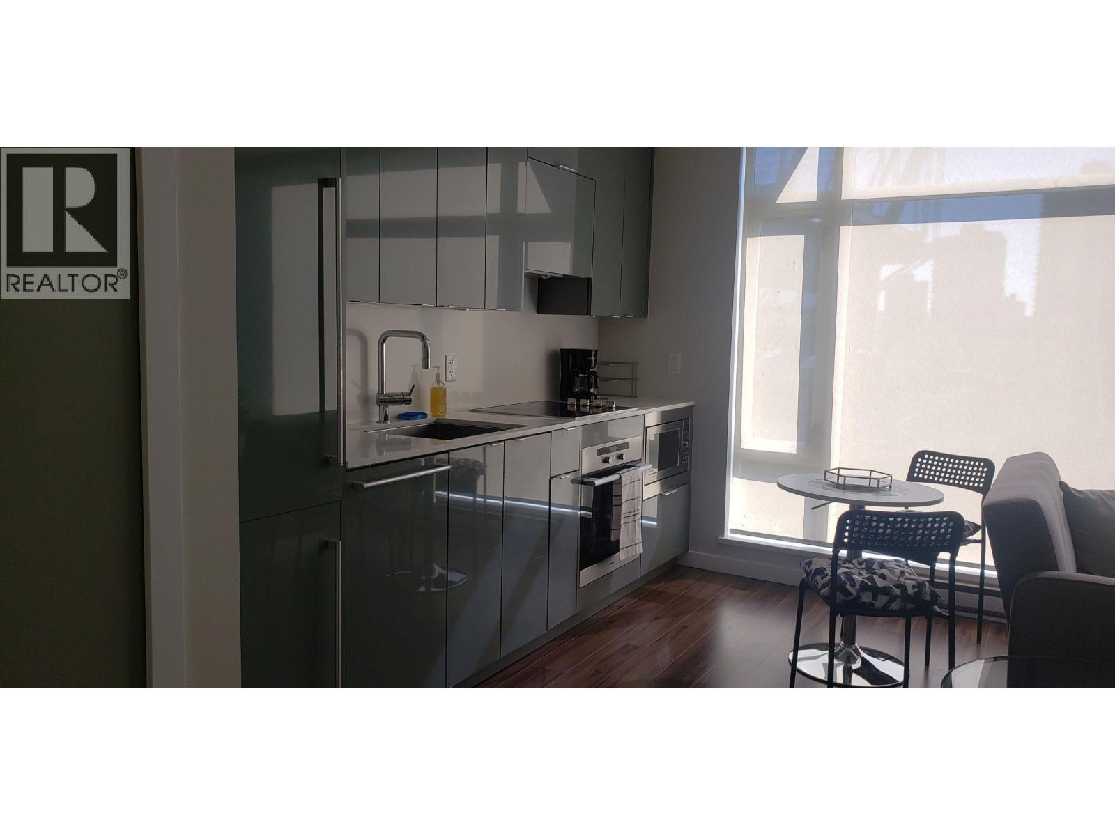 A modern kitchen with a glass cabinet and a table with two chairs.